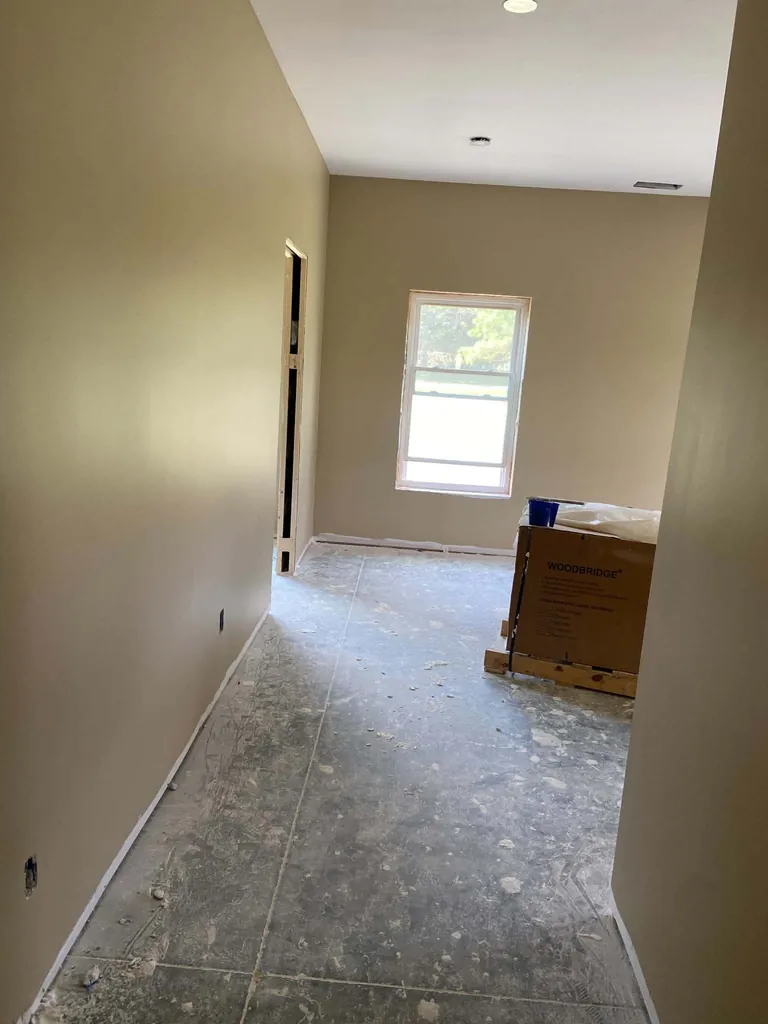 Hallway with finished drywall and fresh paint leading to a window